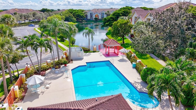 view of pool with a water view, a storage unit, and a patio area