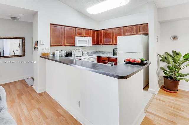 kitchen featuring light hardwood / wood-style floors, kitchen peninsula, white appliances, a textured ceiling, and vaulted ceiling