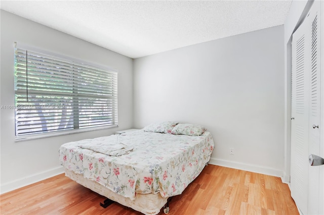 bedroom with hardwood / wood-style flooring, a closet, and a textured ceiling