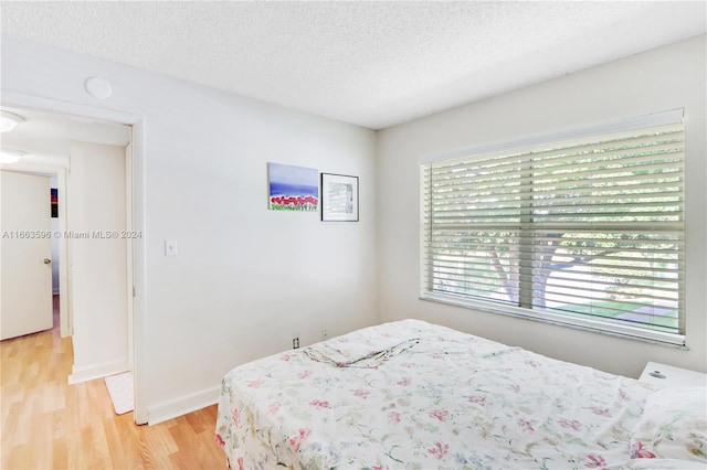 bedroom with a textured ceiling and light hardwood / wood-style flooring