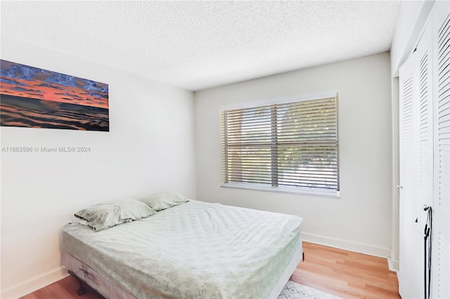 bedroom with a textured ceiling, a closet, and hardwood / wood-style floors