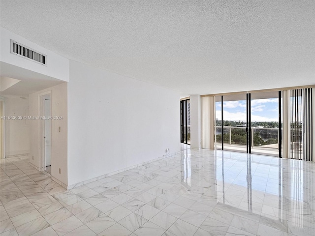 spare room with floor to ceiling windows and a textured ceiling