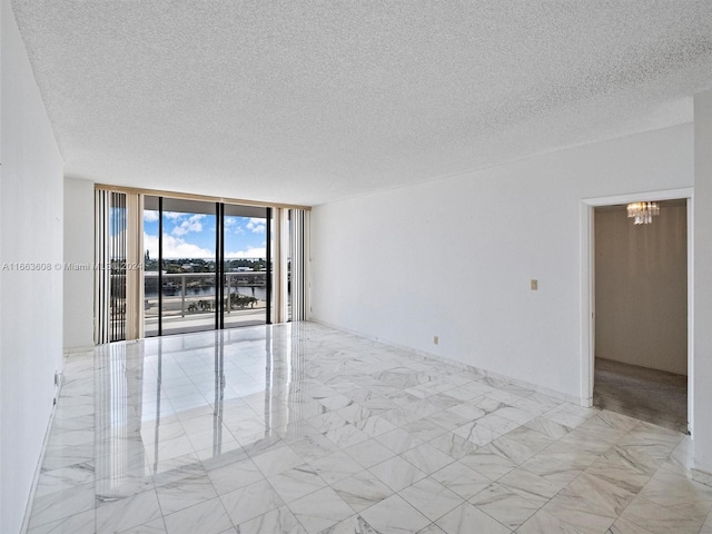 unfurnished room with a textured ceiling, floor to ceiling windows, and a chandelier