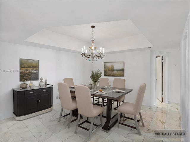 dining area with a notable chandelier and a raised ceiling