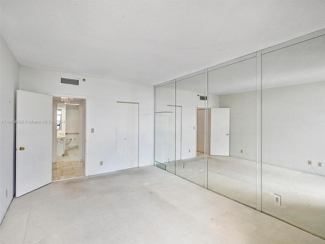 unfurnished bedroom with a textured ceiling and connected bathroom