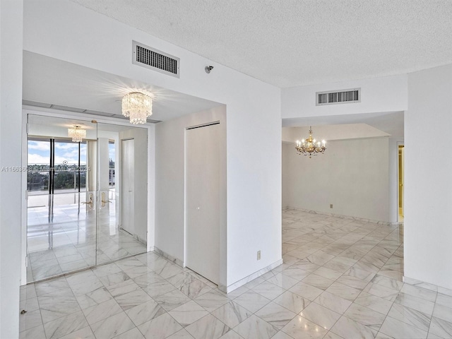 empty room with a textured ceiling and a chandelier