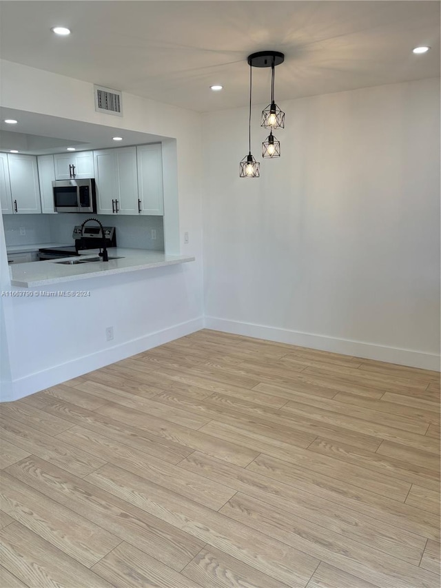 kitchen featuring light hardwood / wood-style flooring, white cabinets, decorative light fixtures, and sink