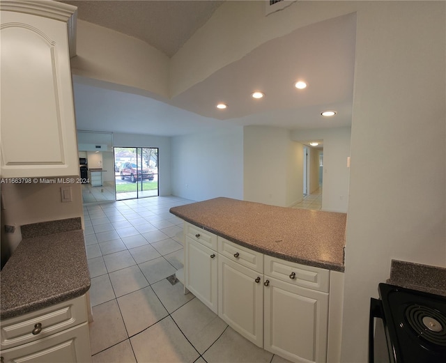 kitchen with stove, white cabinetry, and light tile patterned floors