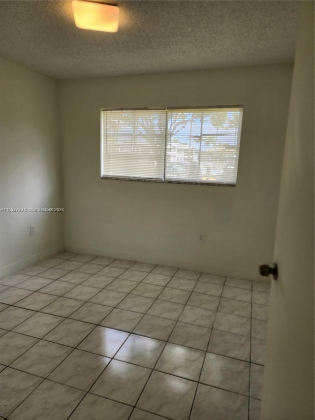 empty room featuring light tile patterned floors and a textured ceiling