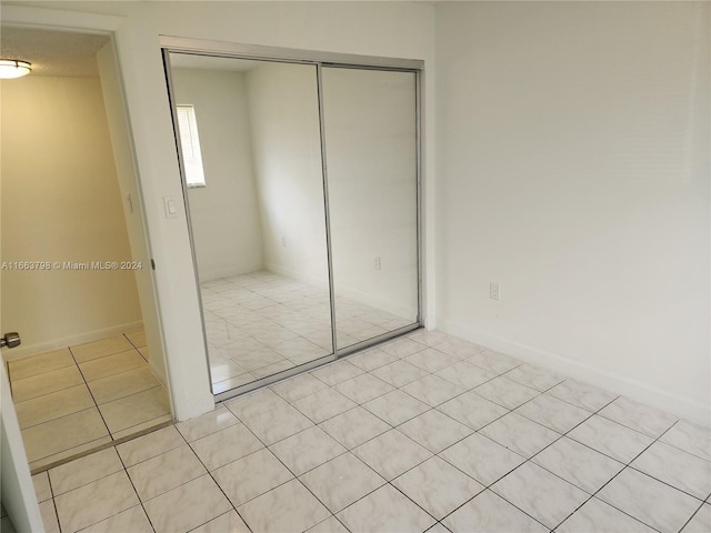 unfurnished bedroom featuring a closet and light tile patterned floors