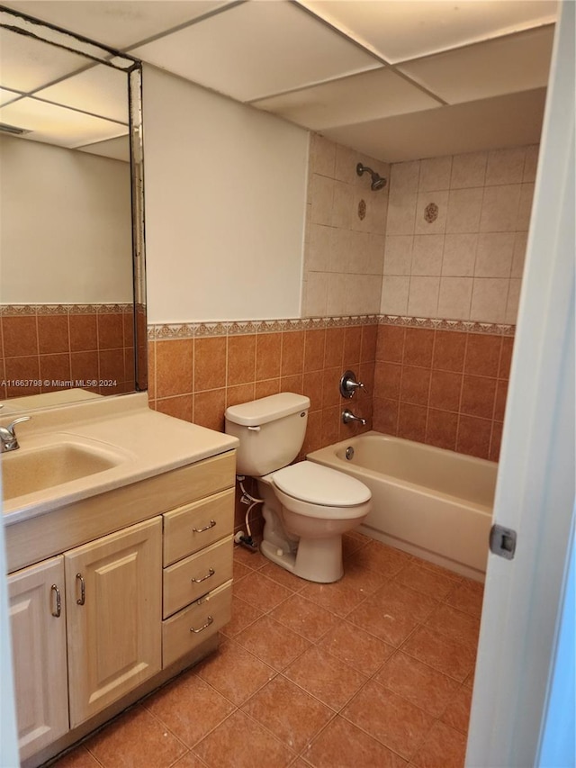 full bathroom with tile patterned floors, vanity, tile walls, toilet, and tiled shower / bath