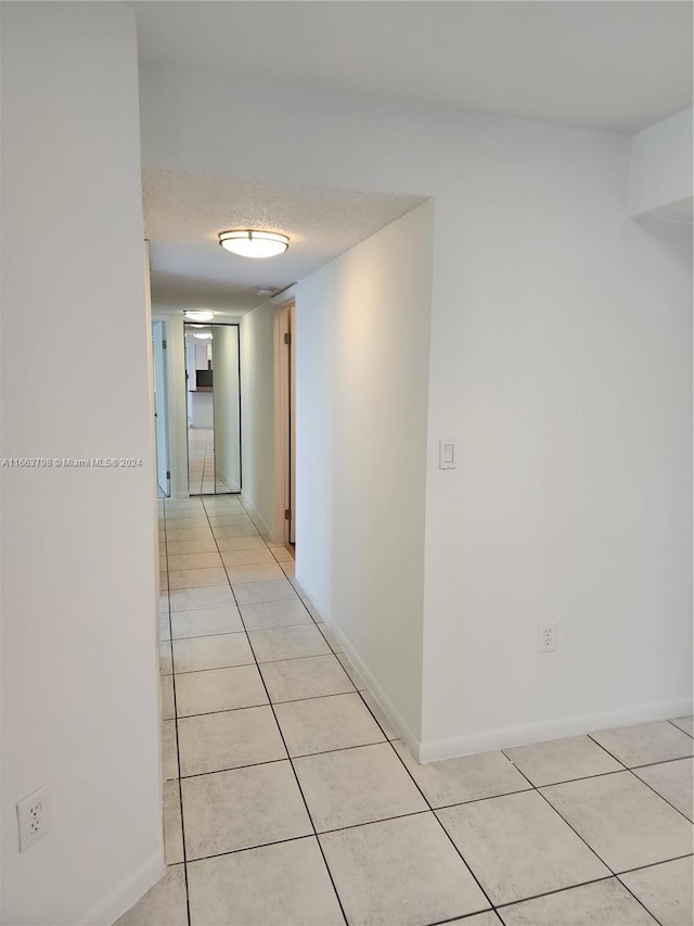 hall featuring light tile patterned flooring and a textured ceiling