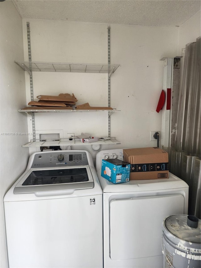 laundry area with a textured ceiling and washing machine and dryer