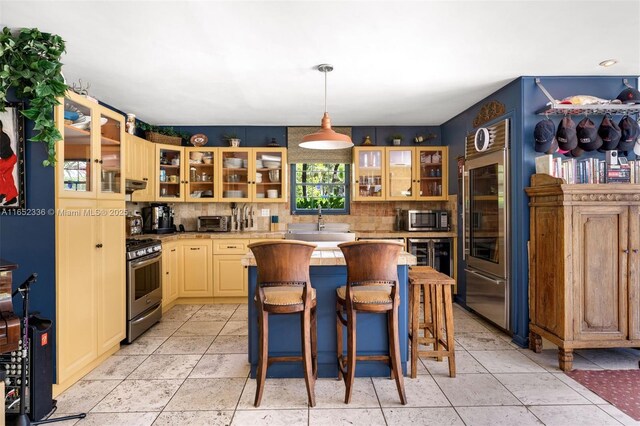 kitchen featuring pendant lighting, a breakfast bar area, stainless steel appliances, a center island, and light brown cabinets