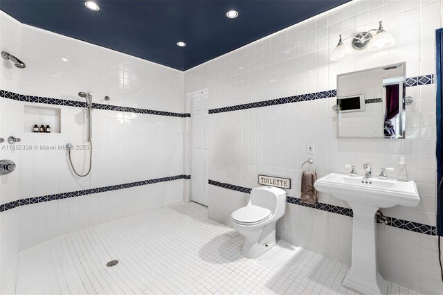 bathroom with sink, tile walls, tile patterned flooring, tiled shower, and toilet