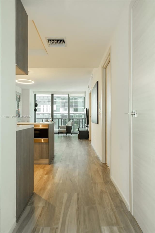 hallway with light hardwood / wood-style flooring and floor to ceiling windows