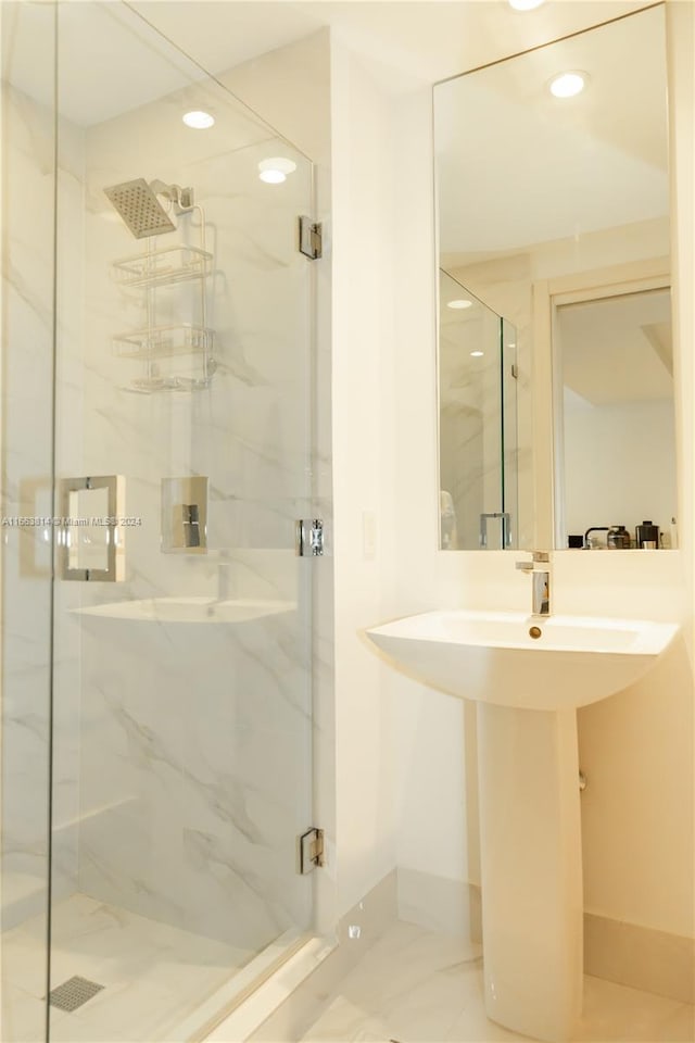 bathroom featuring a shower with shower door and sink