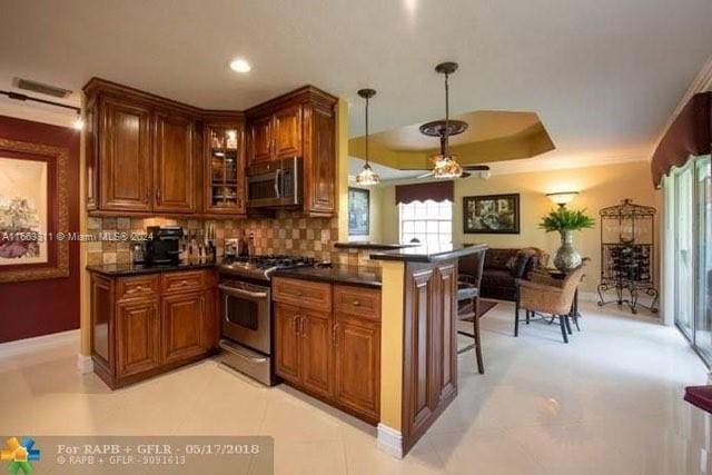 kitchen featuring appliances with stainless steel finishes, backsplash, kitchen peninsula, and a kitchen bar