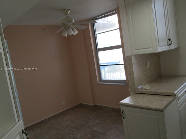 kitchen featuring decorative backsplash, white cabinetry, and ceiling fan