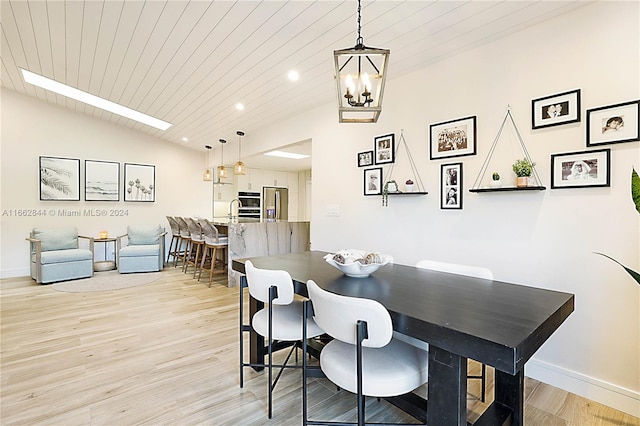 dining space with a chandelier, light hardwood / wood-style floors, vaulted ceiling, and wood ceiling