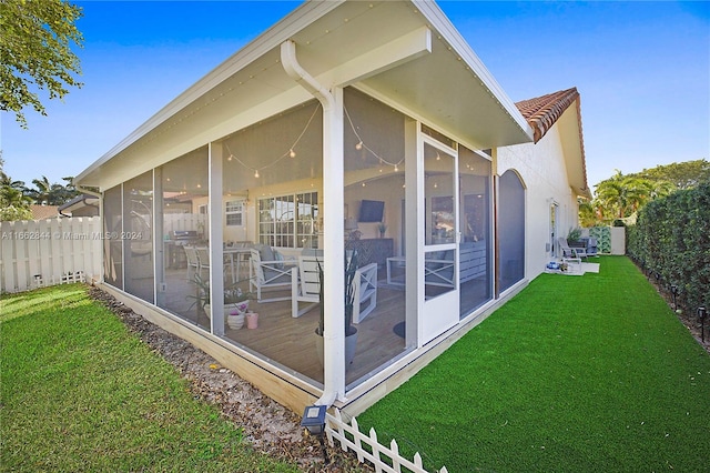 rear view of property featuring a lawn and a sunroom