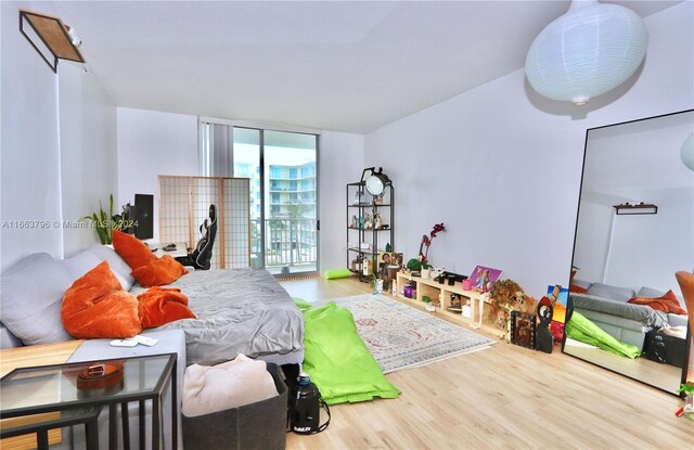 bedroom featuring access to outside, wood-type flooring, and a wall of windows