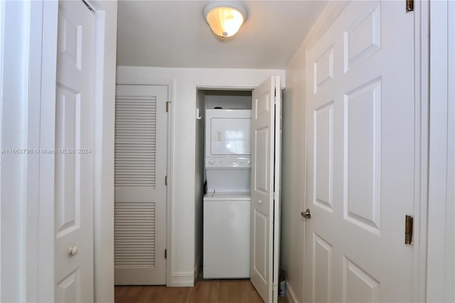 clothes washing area featuring stacked washer and clothes dryer and light wood-type flooring