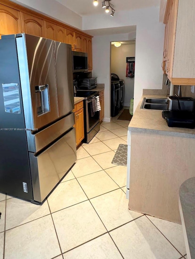 kitchen featuring independent washer and dryer, a sink, appliances with stainless steel finishes, light countertops, and light tile patterned floors