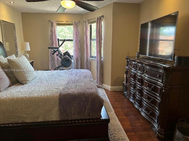 bedroom with ceiling fan, a textured ceiling, and dark hardwood / wood-style floors