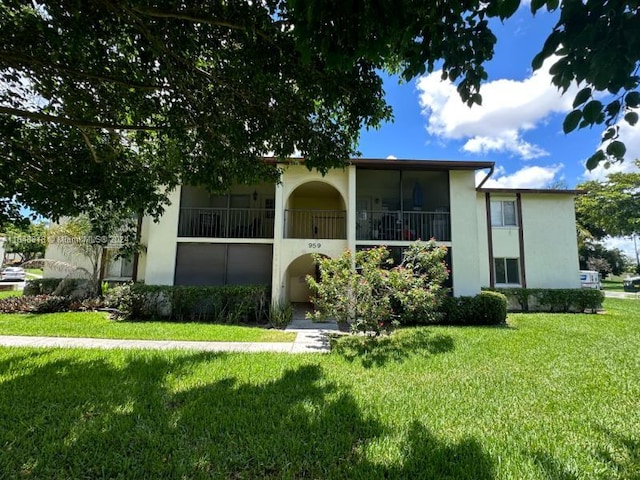 view of front of property with a front yard and a balcony