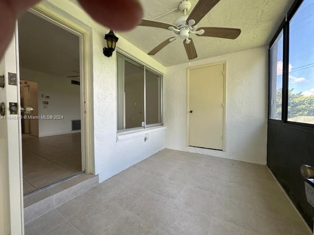 unfurnished sunroom featuring ceiling fan