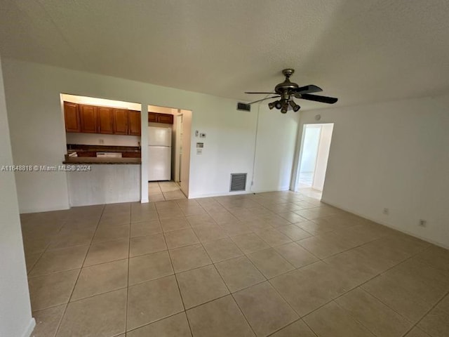unfurnished living room with ceiling fan, visible vents, and light tile patterned floors