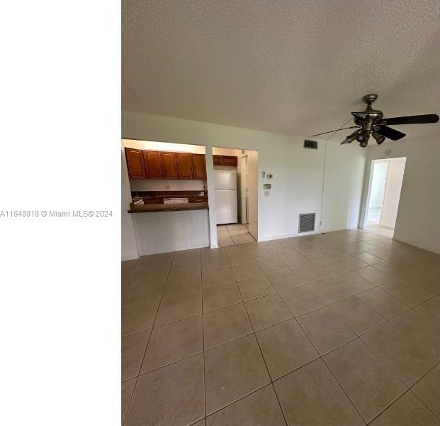 interior space featuring ceiling fan, a textured ceiling, and light tile patterned floors