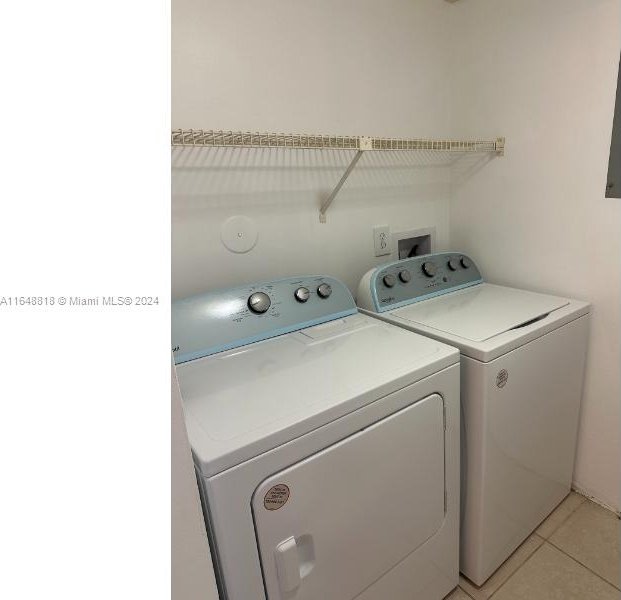 laundry area featuring washing machine and clothes dryer and light tile patterned floors