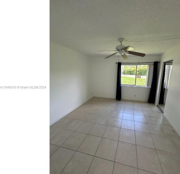 tiled empty room featuring ceiling fan and a textured ceiling