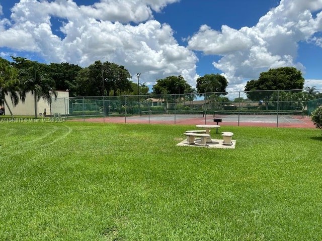 exterior space with fence, a tennis court, and a yard