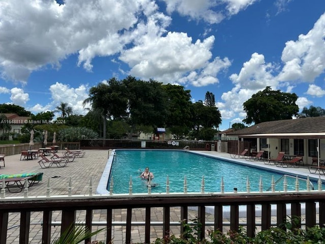 community pool with fence and a patio area