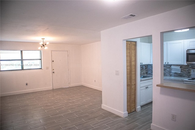 spare room with a notable chandelier and light wood-type flooring