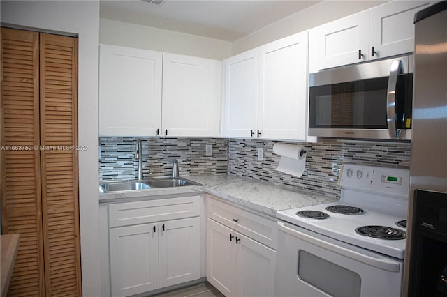 kitchen with electric stove, sink, decorative backsplash, and white cabinetry