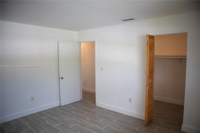 unfurnished bedroom featuring wood-type flooring, a closet, and a walk in closet