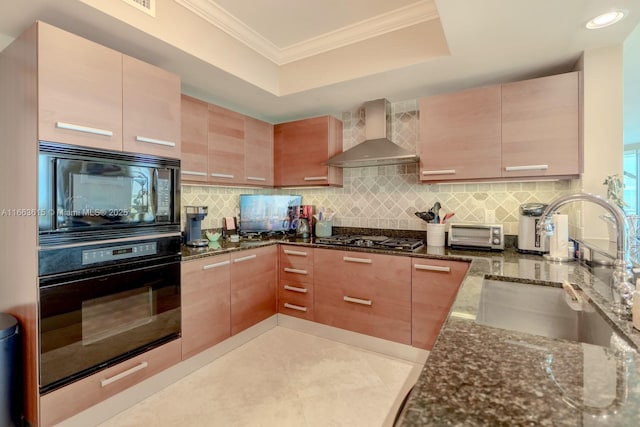 kitchen featuring black appliances, wall chimney range hood, sink, a raised ceiling, and dark stone counters