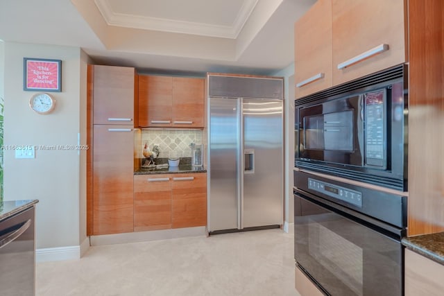 kitchen with black appliances, a raised ceiling, and dark stone countertops