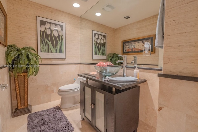 bathroom with toilet, tile walls, and vanity