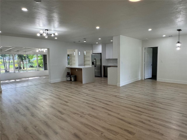 unfurnished living room featuring a chandelier and light hardwood / wood-style floors