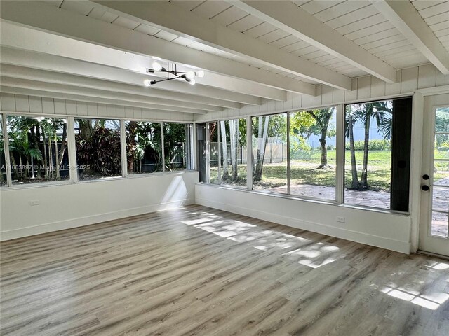 unfurnished sunroom featuring beamed ceiling, a wealth of natural light, and a notable chandelier