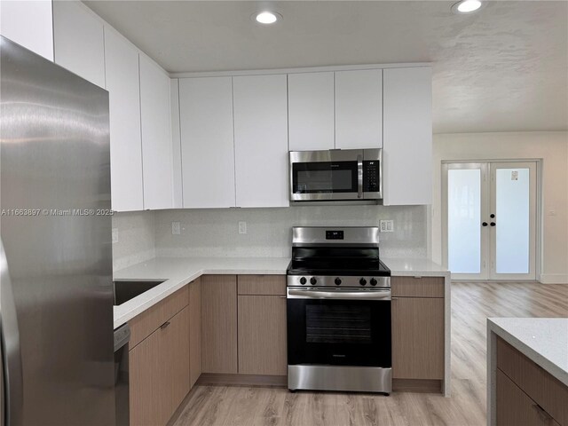 kitchen with backsplash, light hardwood / wood-style floors, white cabinetry, and stainless steel appliances