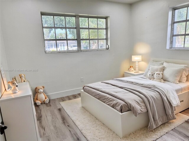 bedroom with multiple windows and light hardwood / wood-style floors