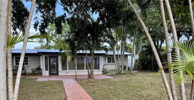 rear view of property featuring a sunroom, a yard, and solar panels