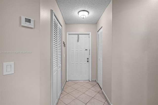 corridor with a textured ceiling and light tile patterned floors