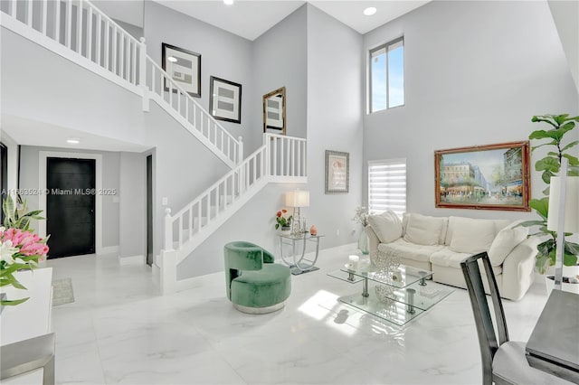 living area with recessed lighting, a towering ceiling, baseboards, stairs, and marble finish floor